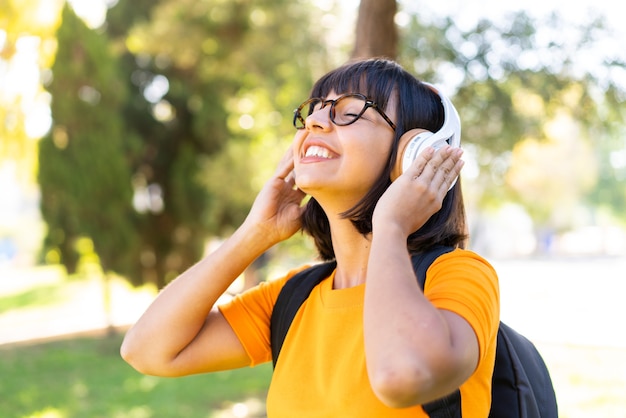 Młoda brunetka kobieta słucha muzyki na świeżym powietrzu