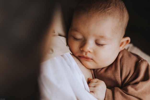 Młoda brunetka mama i jej nowo narodzone dziecko w jej ramionach Zdjęcie domu w ciemnym pokoju przy oknie