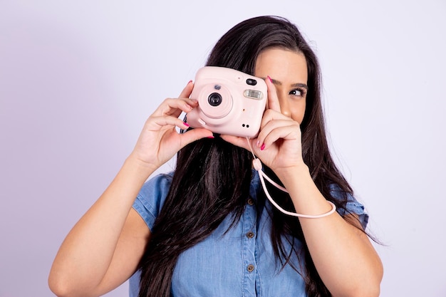 Młoda brunetka pozuje z aparatem polaroidowym wysokiej jakości zdjęciem