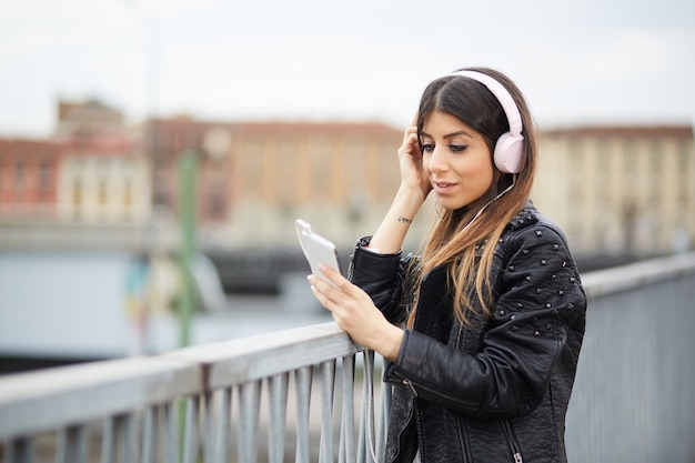 Młoda brunetka słucha muzyki przez słuchawki w środowisku miejskim
