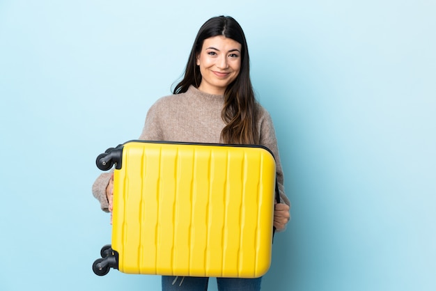 Młoda brunetki dziewczyna nad odosobnionym błękitem w wakacje z podróży walizką