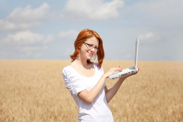 Młoda businesswoman w kolorze białym pracy z notebookiem w polu pszenicy.