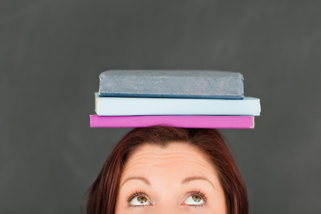 Zdjęcie młoda caucasian jest ubranym książki na jej głowie z kamerą skupiał się na wierzchołku głowa