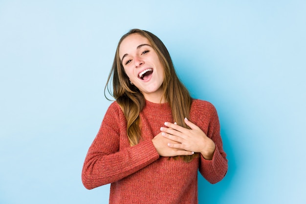 Młoda caucasian kobieta pozuje śmiać się utrzymujący ręki na sercu