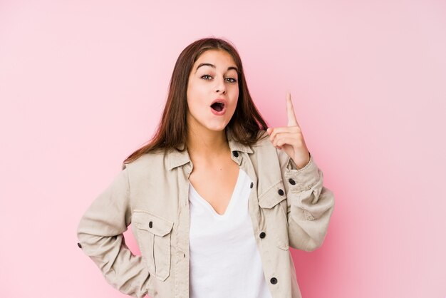 Młoda caucasian kobieta pozuje w różowej ścianie ma pomysł