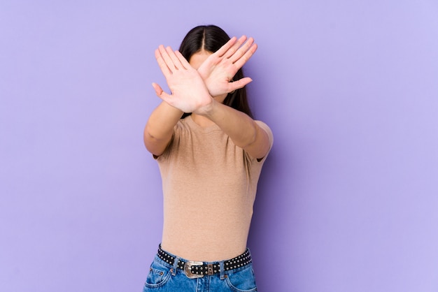 Młoda caucasian kobieta utrzymuje dwa ręki krzyżować na purpury ścianie