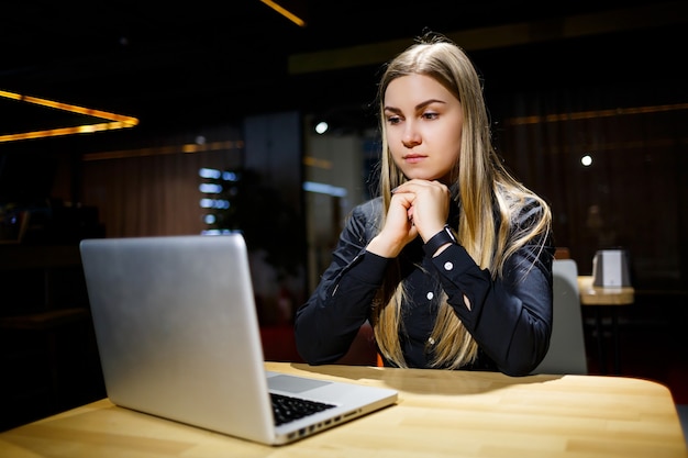 Młoda celowa kobieta pracuje nad nowym projektem biznesowym w biurze. Ubrany w czarną koszulę.