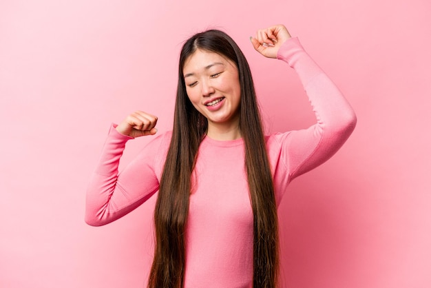 Młoda Chinka odizolowana na różowym tle świętująca wyjątkowy dzień podskakuje i wznosi ręce z energią