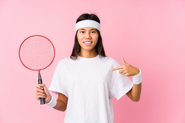 Młoda Chińska Kobieta Bawić Się Badminton W Różowej ściennej Osobie Wskazuje Ręcznie Koszulowa Kopii Przestrzeń, Dumny I Ufny