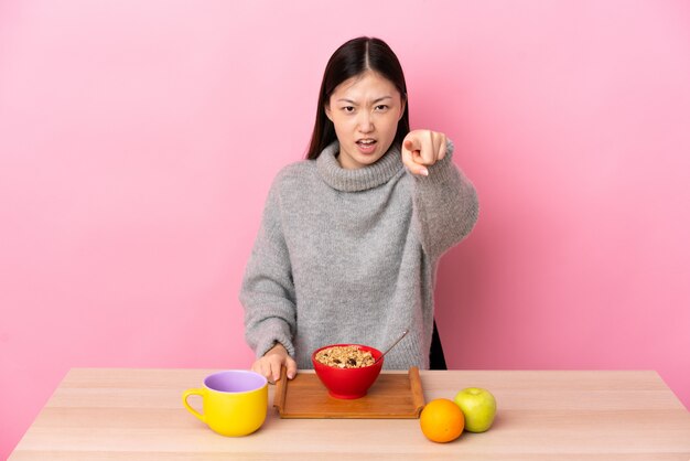 Młoda Chińska Kobieta Ma śniadanie W Stole Udaremniającym I Wskazuje Przód
