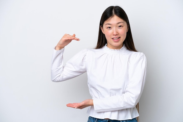 Młoda chińska kobieta odizolowywająca na białym tle trzyma copyspace wstawiać reklamę