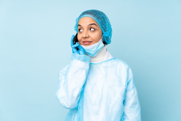 Młoda chirurg kobieta w niebieskim mundurze prowadzenie rozmowy z telefonem komórkowym z kimś