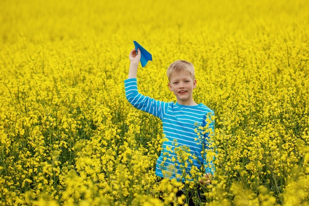 Młoda chłopiec z papierowym samolotem przeciw niebieskiemu niebu