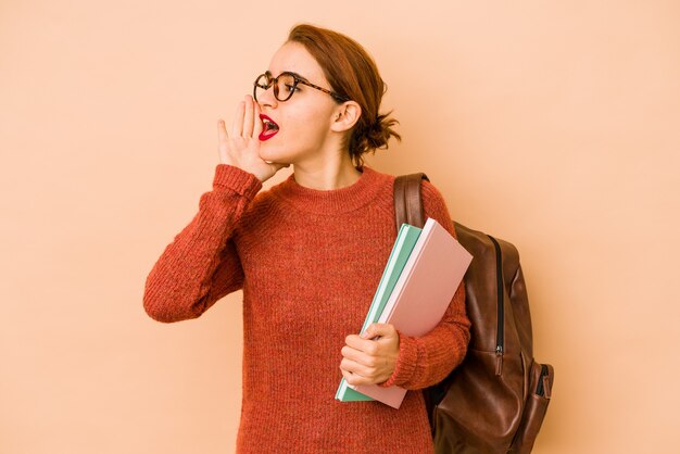 Młoda chuda arabska studentka krzyczy i trzyma dłoń w pobliżu otwartych ust.