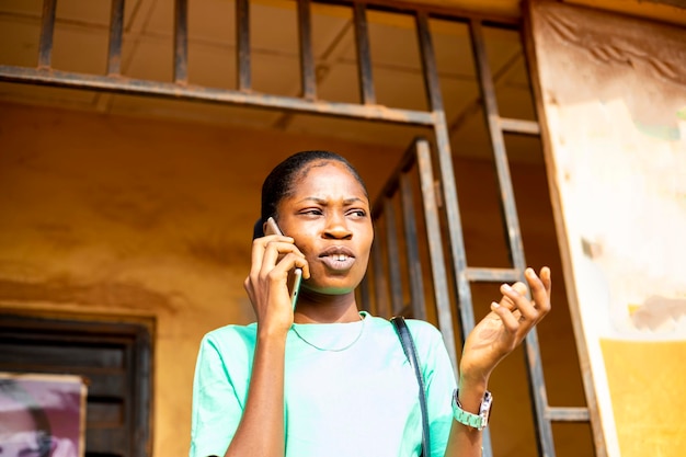 Młoda czarna Afrykanka sprawdza zawartość w mediach społecznościowych, rozmawiając z przyjacielem online za pomocą telefonu komórkowego