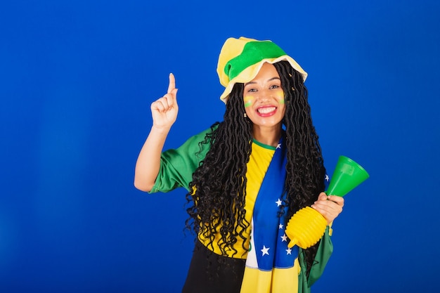 Młoda czarna brazylijska fanka piłki nożnej tańczy z uniesionymi palcami
