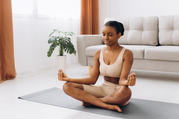 Młoda czarna kobieta medytuje w domu, koncepcja jogi online, wolna przestrzeń