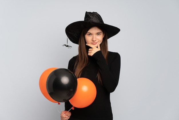 Młoda czarownica trzyma czarne i pomarańczowe balony powietrzne