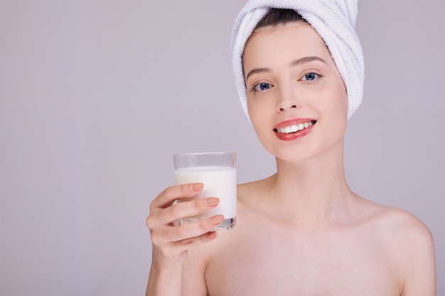 Młoda dama po prysznicu trzyma szklankę z mlekiem.