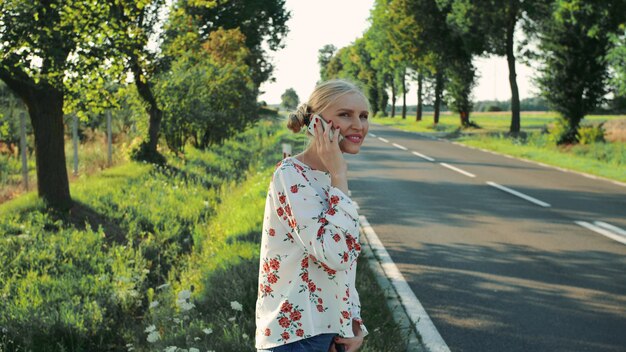 Młoda dama rozmawia przez telefon podczas podróży autostopem.