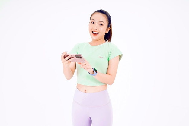 Młoda dama z Azji pokazuje pusty ekran smartfona z pozytywnym wyrazem twarzy, uśmiecha się szeroko ubrany w zwykłą odzież, czując szczęście na niebieskim tle Telefon komórkowy z białym ekranem w kobiecej dłoni