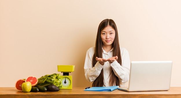 Młoda dietetyk chińska kobieta pracuje z jej laptopu mieniem coś z palmami