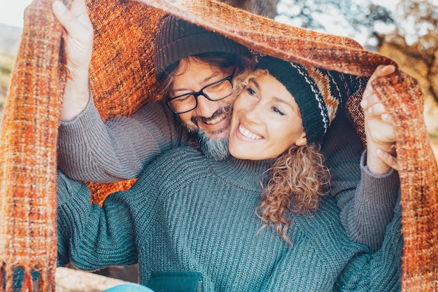 Zdjęcie młoda dojrzała szczęśliwa para cieszy się razem spędzaniem wolnego czasu pod kolorową osłoną na świeżym powietrzu przyjaźń i relacje ludzie mężczyzna i kobieta bawią się w miłości grając w zimowym sezonie jesiennym