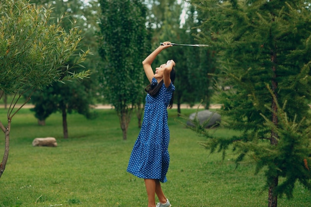 Młoda dorosła kobieta gra w badmintona w parku.