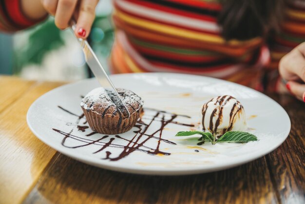 Młoda dorosła kobieta je czekoladową fondant w kawiarni