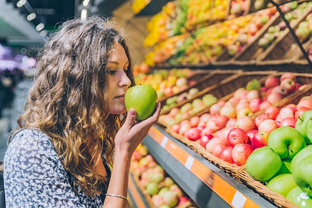 Młoda dorosła kobieta wybierająca jabłka w sklepie spożywczym