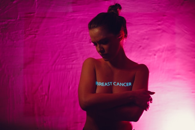 Młoda dorosła kobieta z napisem „Rak piersi” na piersi