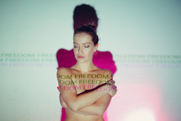 Zdjęcie młoda dorosła kobieta z napisem wolność na swoim ciele