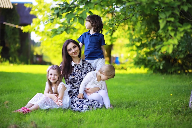Młoda duża rodzina na letni poranny spacer. Piękna mama z dziećmi bawi się w parku.