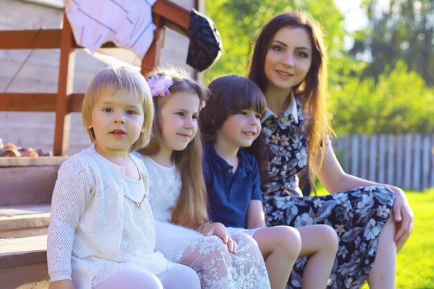 Młoda duża rodzina na letni poranny spacer. Piękna mama z dziećmi bawi się w parku.