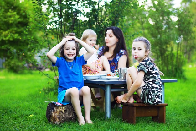 Młoda duża rodzina na pikniku w letni poranek. Piękna mama z dziećmi je śniadanie w parku.