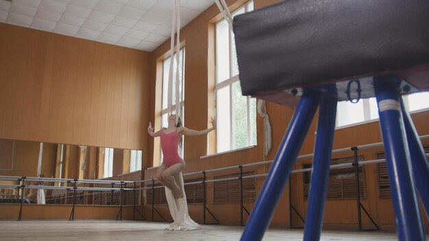 Zdjęcie młoda dziewczyna akrobata pokazuje elastyczność na obręczy gimnastycznej, ujęcie teleobiektywem
