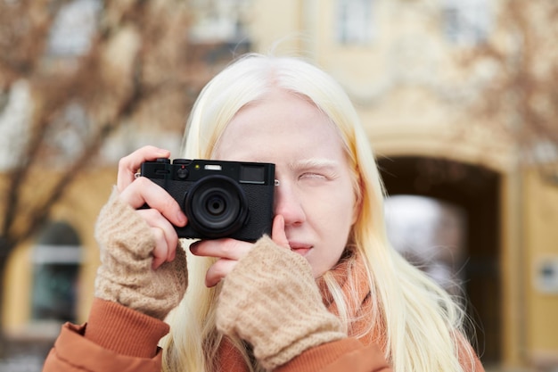 Młoda dziewczyna albinos z długimi blond włosami fotografuje coś