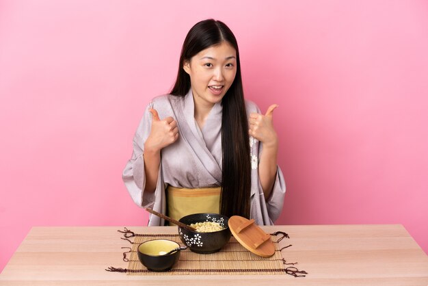 Młoda Dziewczyna Chiński Na Sobie Kimono I Jedzenie Makaronu, Dając Kciuk Do Góry Gestu