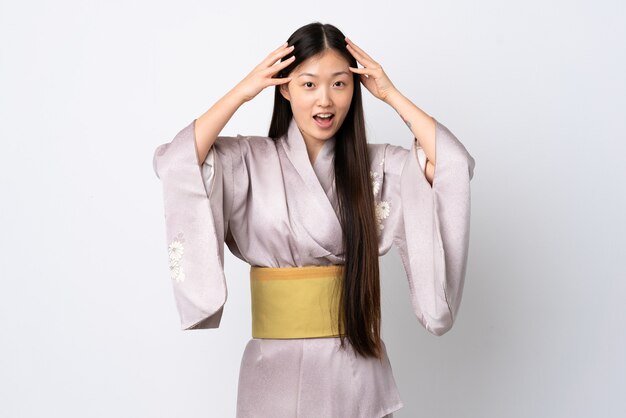 Młoda dziewczyna chiński na sobie kimono na białym tle z wyrazem zaskoczenia