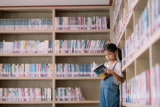 Zdjęcie młoda dziewczyna czyta książkę w bibliotece