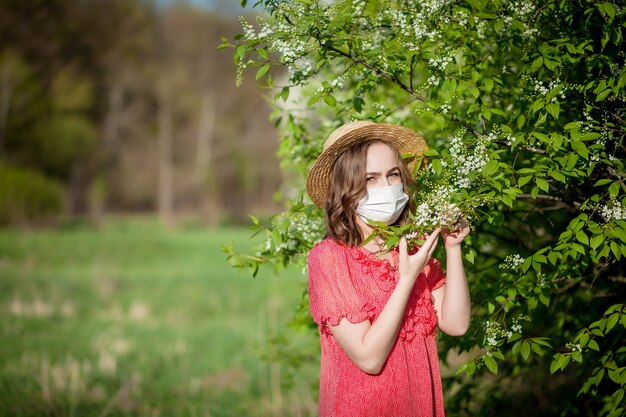 Młoda dziewczyna dmuchanie w nos i kichanie w tkance przed kwitnącym drzewem