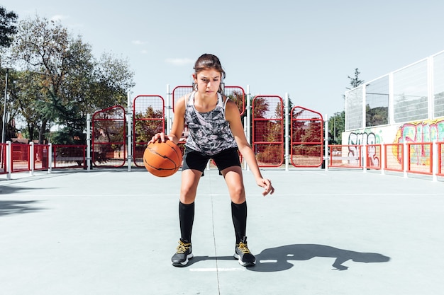 Młoda dziewczyna gra w koszykówkę na boisku do koszykówki