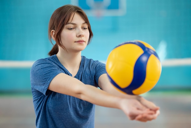 Zdjęcie młoda dziewczyna grająca w siatkówkę w pomieszczeniu zdjęcie kobiety ćwiczącej umiejętności siatkówki trenującej kopanie piłką