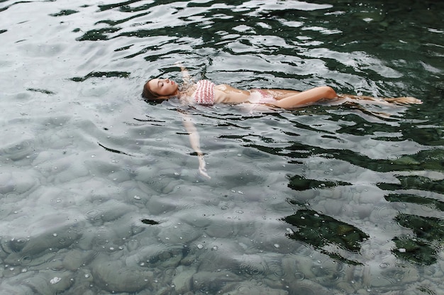 Młoda dziewczyna pływa w morzu w deszczu