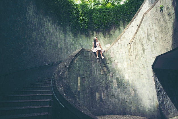 Młoda dziewczyna podróżnik siedzi na schodach z kręgu spiralnych schodów podziemnego krzyża
