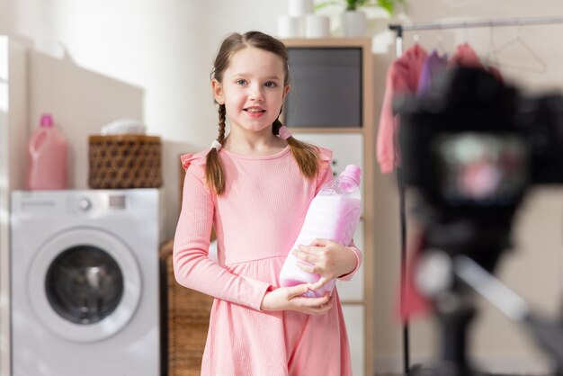 Młoda dziewczyna pracuje jako influencerka w mediach społecznościowych, uśmiechając się do kamery, trzyma detergent do prania