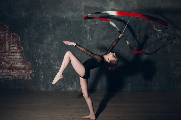 Młoda dziewczyna profesjonalna gimnastyczka kobieta gimnastyka artystyczna ze wstążką w studio
