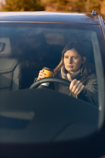 Młoda Dziewczyna Rano Jedzie Do Pracy Samochodem I Pije Kawę Widok Przez Przednią Szybę