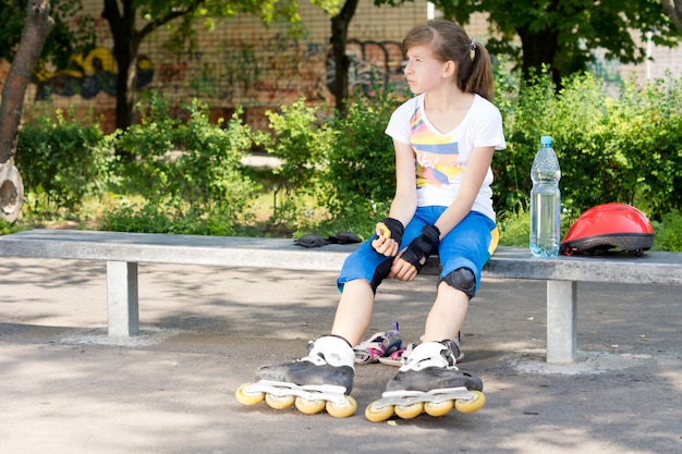 Młoda Dziewczyna Rolkarz Odpoczywa Na ławce W Parku