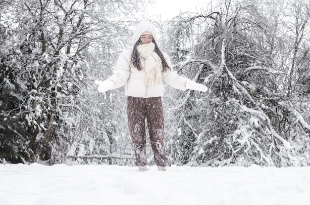 Młoda dziewczyna rzuca śnieg w zimowym lesie